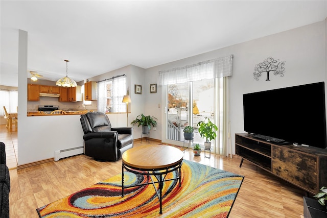 living room featuring baseboard heating, light hardwood / wood-style floors, and ceiling fan