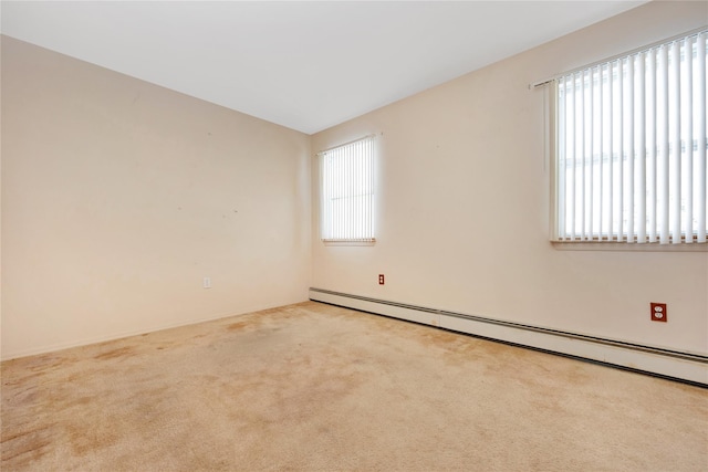 spare room with light colored carpet, a wealth of natural light, and a baseboard heating unit