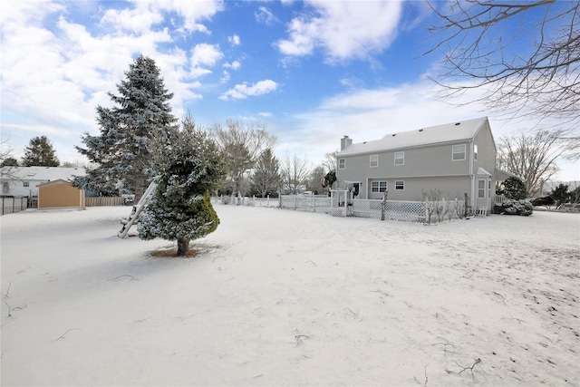 snowy yard featuring a shed