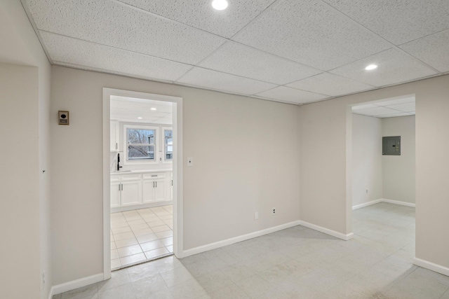 empty room with sink, electric panel, and a drop ceiling