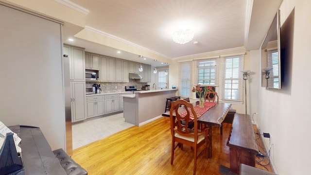 dining area with ornamental molding and light wood-type flooring