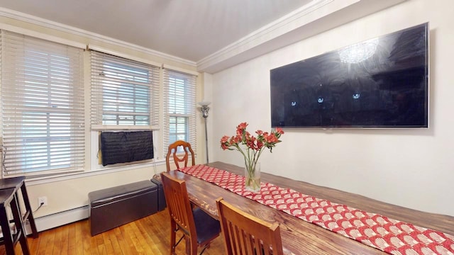 dining space featuring a baseboard heating unit, ornamental molding, and hardwood / wood-style floors