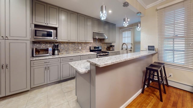 kitchen featuring crown molding, decorative light fixtures, kitchen peninsula, stainless steel appliances, and light stone countertops