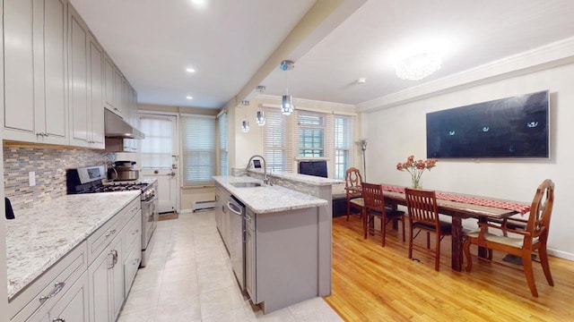 kitchen featuring pendant lighting, sink, gray cabinets, appliances with stainless steel finishes, and a center island with sink