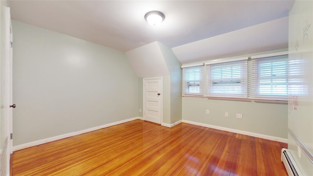 interior space with a baseboard radiator, lofted ceiling, and wood-type flooring