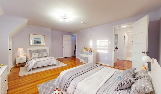 bedroom with ensuite bath and light wood-type flooring