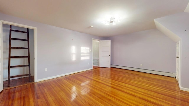 empty room featuring baseboard heating and hardwood / wood-style flooring