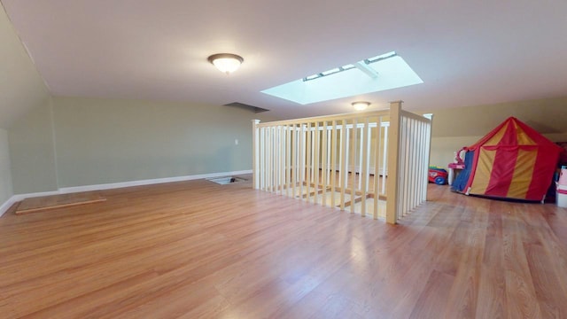 additional living space featuring a skylight and light wood-type flooring