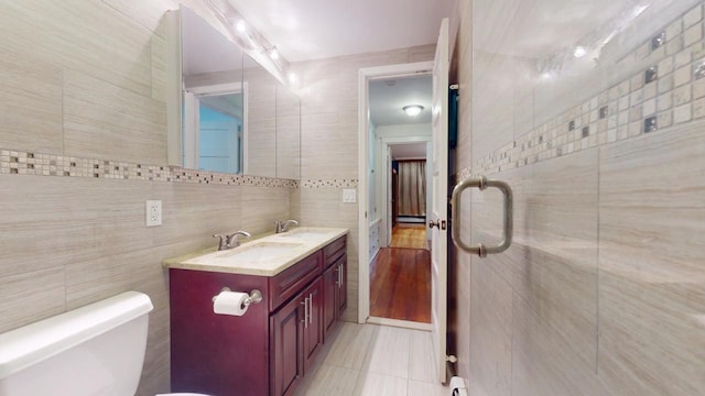 bathroom with tile patterned floors, toilet, tile walls, a baseboard radiator, and vanity