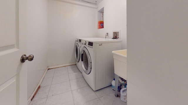 clothes washing area featuring washer and clothes dryer and light tile patterned floors