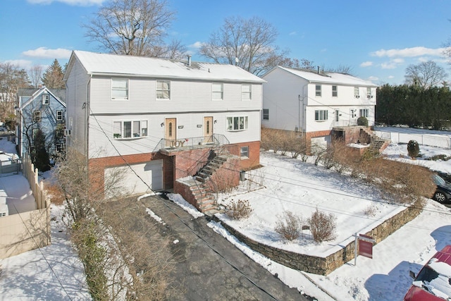 snow covered rear of property with a garage