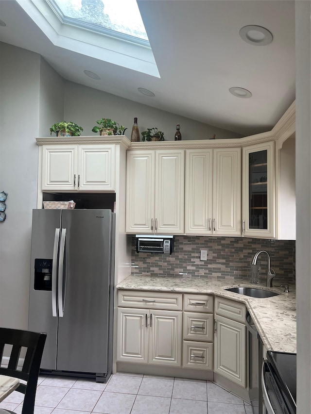 kitchen with stainless steel refrigerator with ice dispenser, range with electric stovetop, lofted ceiling with skylight, sink, and tasteful backsplash