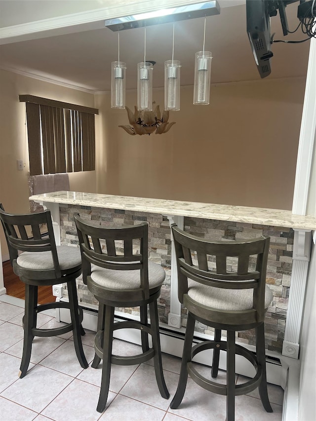 bar featuring pendant lighting, dark brown cabinetry, light tile patterned floors, and ornamental molding