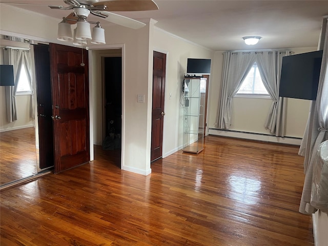 interior space with ceiling fan, a baseboard radiator, wood-type flooring, and crown molding