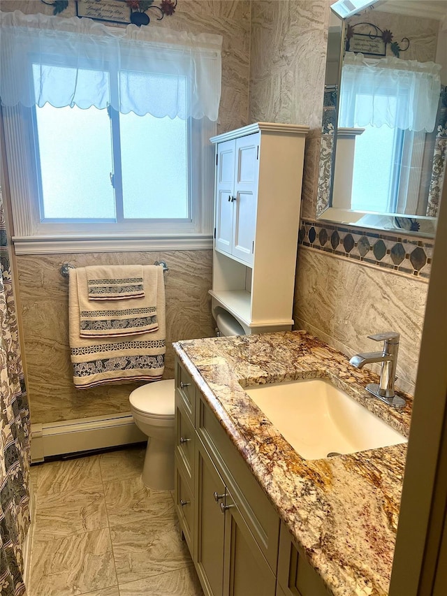 bathroom featuring baseboard heating, a healthy amount of sunlight, toilet, and vanity