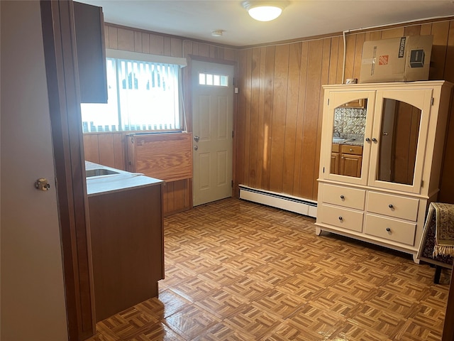 interior space with light parquet floors, a baseboard heating unit, and wooden walls