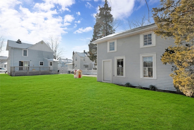 rear view of house featuring a wooden deck and a yard