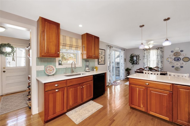 kitchen with pendant lighting, sink, plenty of natural light, black dishwasher, and tasteful backsplash