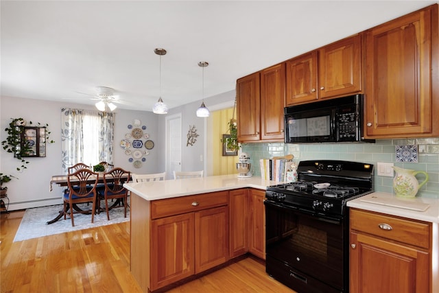 kitchen with tasteful backsplash, black appliances, kitchen peninsula, and light wood-type flooring