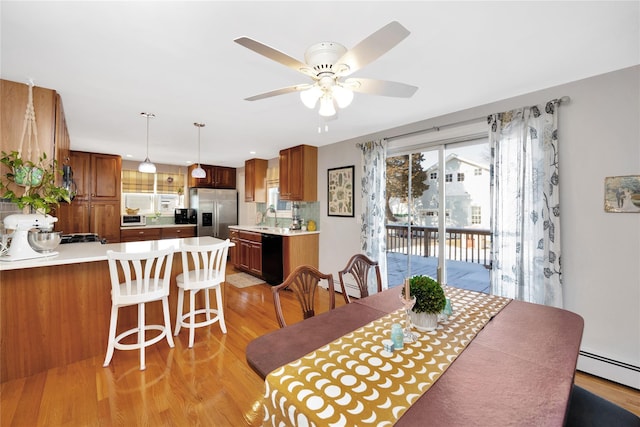 dining area featuring baseboard heating, ceiling fan, sink, and light hardwood / wood-style floors