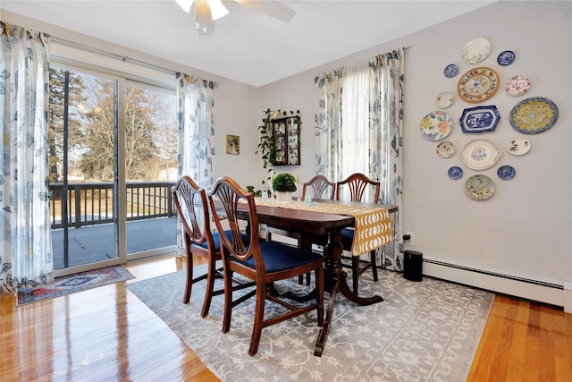 dining area with ceiling fan, a baseboard heating unit, and light wood-type flooring