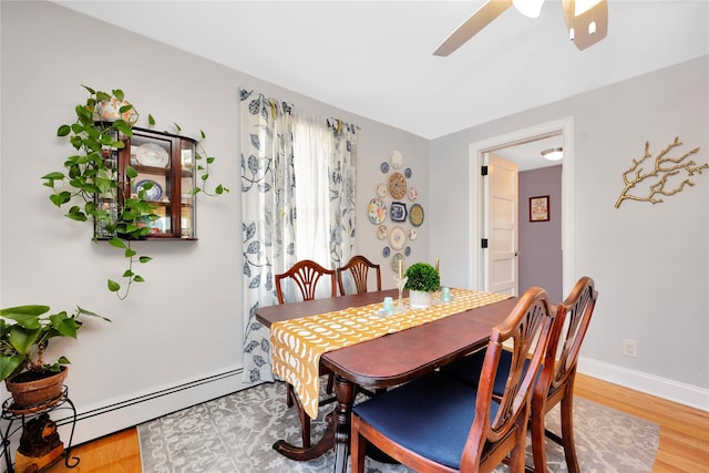 dining space with hardwood / wood-style floors, a baseboard radiator, and ceiling fan