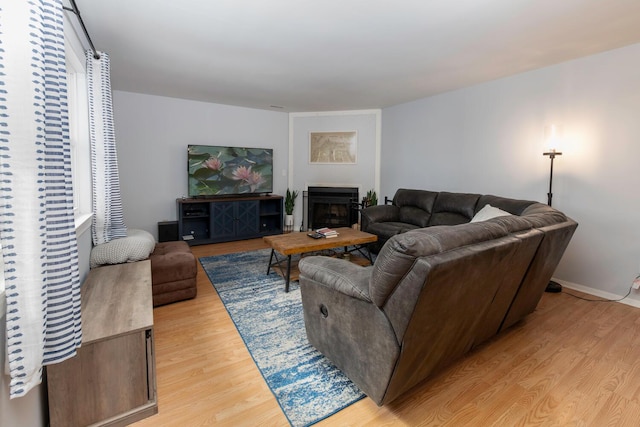 living room featuring a fireplace, baseboards, and light wood-style floors