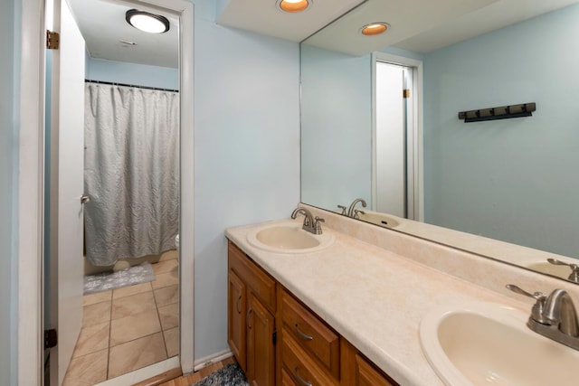 full bath with curtained shower, double vanity, and a sink