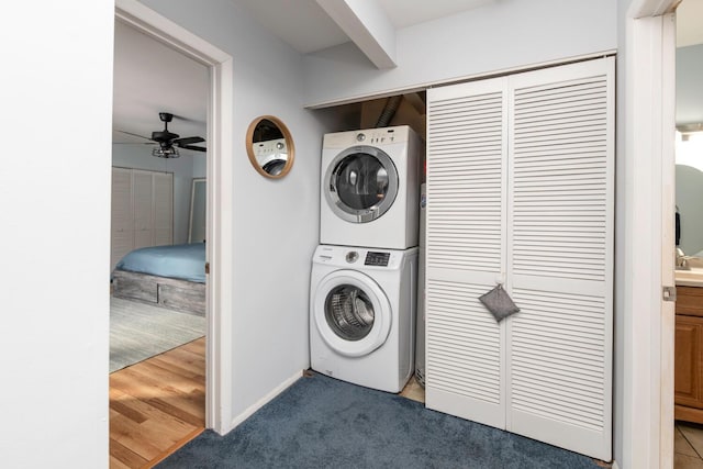 laundry room featuring laundry area, stacked washer / dryer, carpet flooring, and ceiling fan