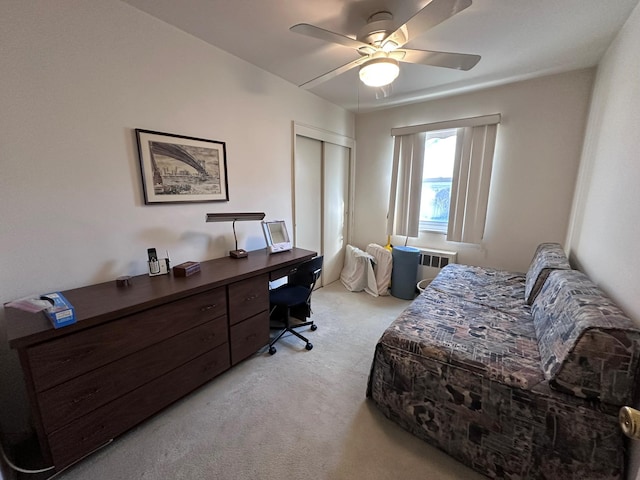 bedroom featuring radiator heating unit, light colored carpet, a closet, and ceiling fan