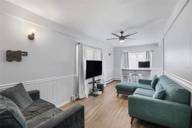 living room featuring ceiling fan, a healthy amount of sunlight, light wood-type flooring, and baseboard heating