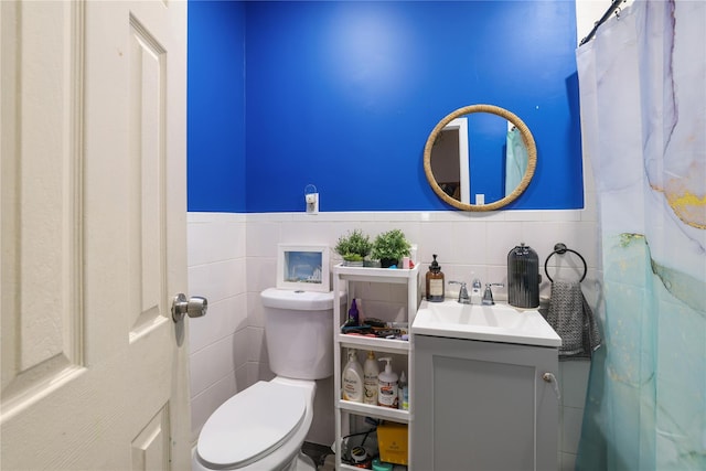 bathroom with vanity, tile walls, and toilet