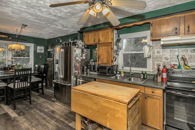 kitchen with sink, dark hardwood / wood-style flooring, decorative backsplash, stainless steel appliances, and a textured ceiling