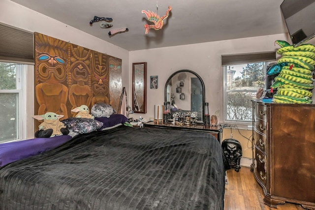 bedroom featuring hardwood / wood-style flooring, a baseboard radiator, and multiple windows