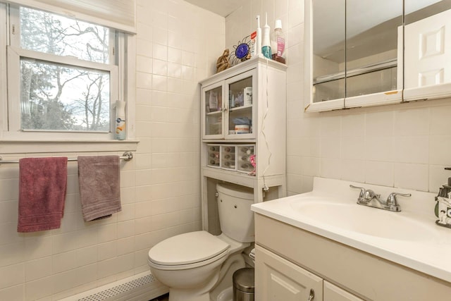 bathroom featuring tile walls, vanity, toilet, and baseboard heating