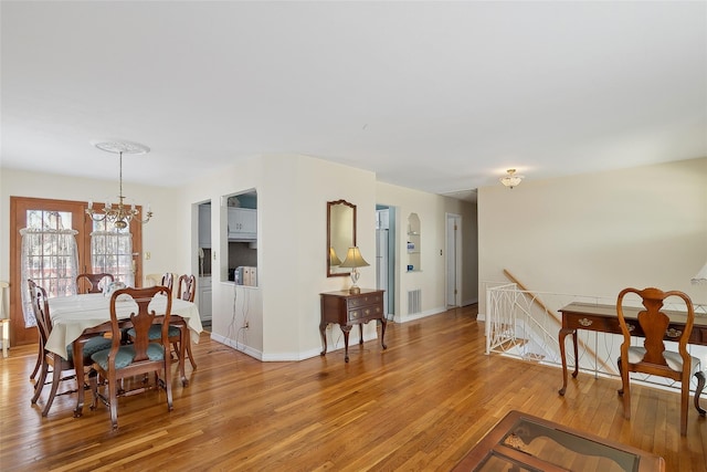 dining area with light wood-type flooring and a notable chandelier