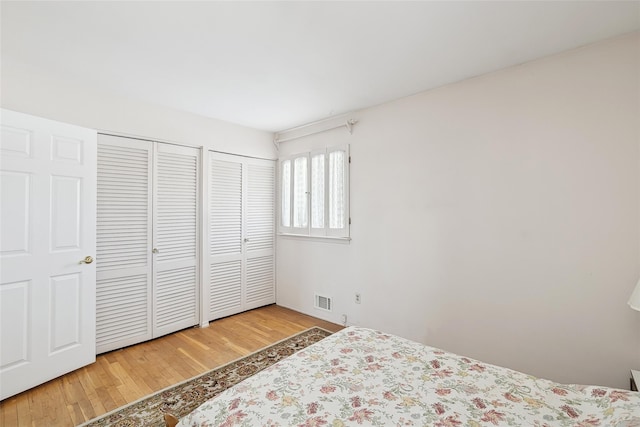 bedroom featuring hardwood / wood-style flooring and two closets