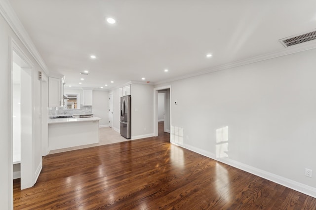 unfurnished living room featuring crown molding and hardwood / wood-style floors