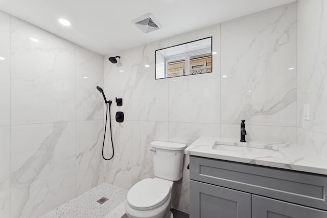 bathroom featuring vanity, tile walls, toilet, and tiled shower