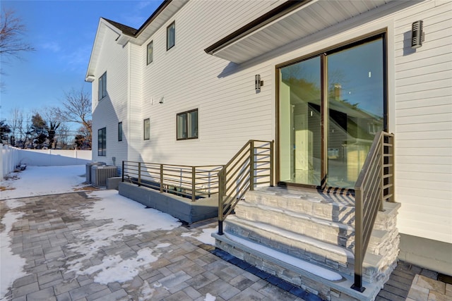 snow covered property entrance featuring a patio and central AC