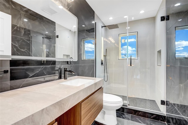 bathroom featuring vanity, a shower with shower door, tile walls, and toilet