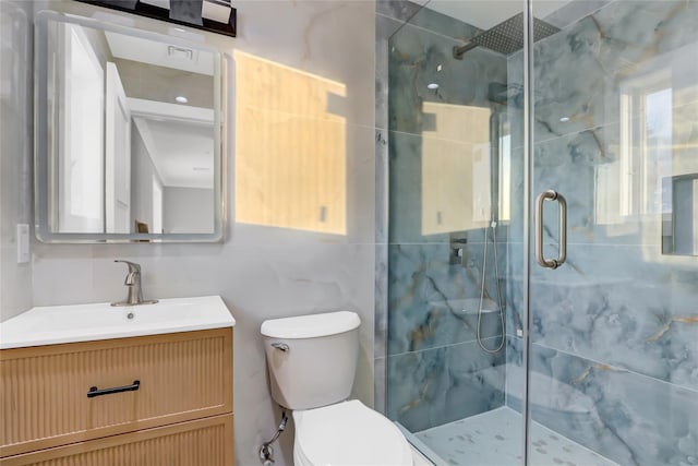 bathroom featuring a shower with door, toilet, and vanity