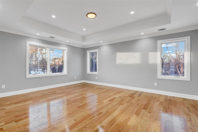 unfurnished room featuring light wood-type flooring, a tray ceiling, and ornamental molding