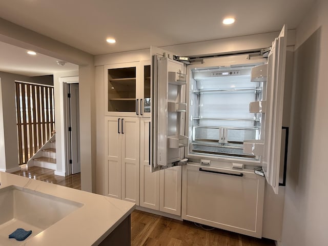 kitchen with dark wood-type flooring, glass insert cabinets, white cabinets, and light countertops