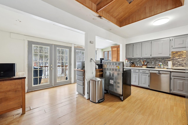 kitchen with light countertops, french doors, decorative backsplash, light wood-style floors, and dishwasher