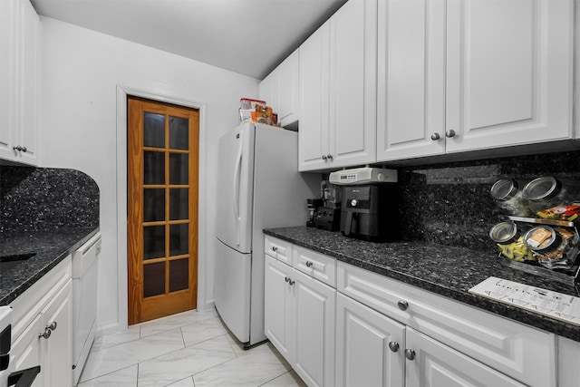 kitchen with white cabinetry, white appliances, dark stone counters, and tasteful backsplash