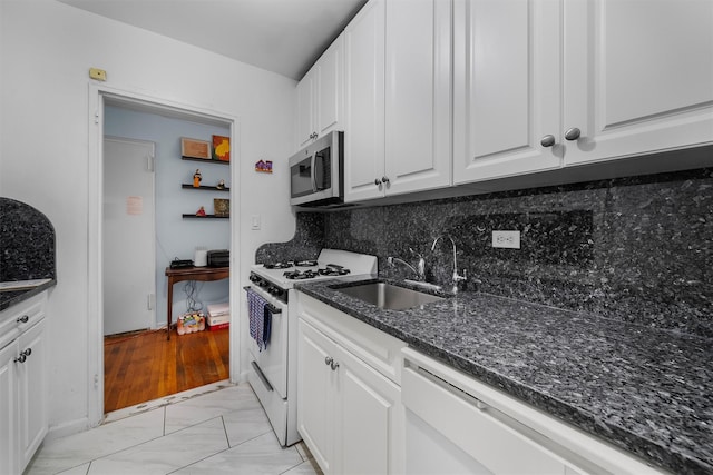 kitchen with sink, white appliances, dark stone countertops, white cabinets, and decorative backsplash