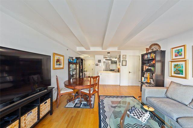 living room with light wood-type flooring and beam ceiling