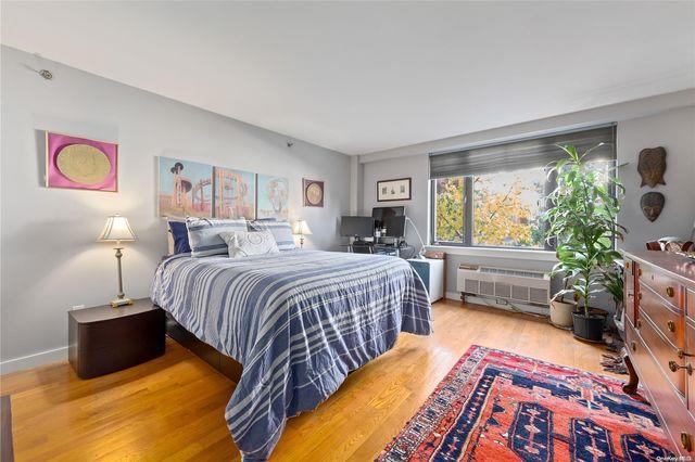 bedroom featuring wood-type flooring and a wall unit AC