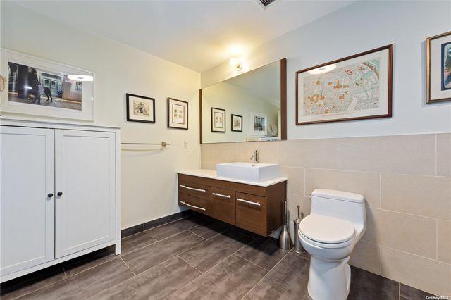 bathroom featuring toilet, tile walls, and vanity